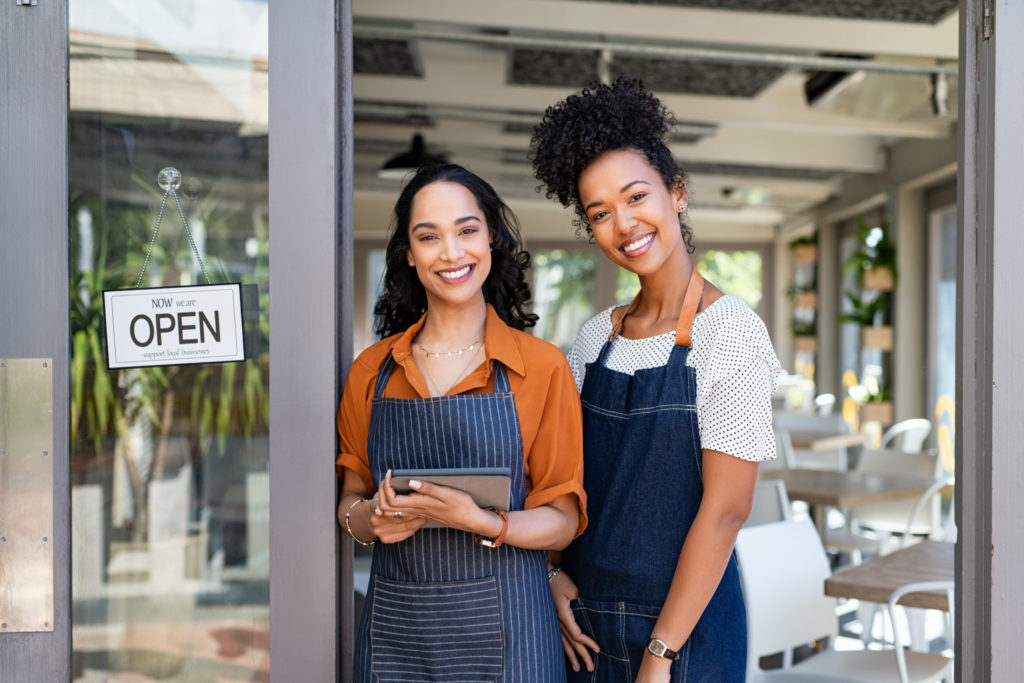 Two successful woman waitress standing at cafe entrance door